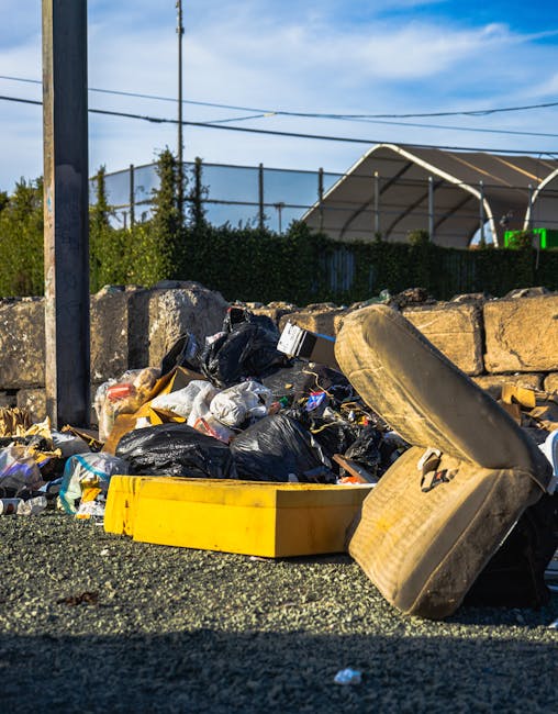 In the image, a collection of discarded waste items is arranged outdoors on a paved surface, possibly part of a rubbish removal or private disposal collection. Visible objects include several large ca