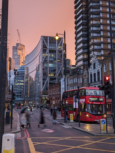 The image depicts the modern glass facade of Westfield, a large shopping centre in Stratford, with the red and white Westfield sign prominently displayed above the entrance. In front of the building,
